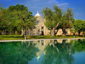 ein Steingebäude mit Bäumen und einem Pool mit Wasser in der Unterkunft Fontana Vecchia B&B in Castellana Grotte