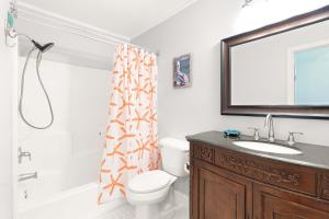 a bathroom with a toilet and a sink and a mirror at Castaway Cottage in Tybee Island +35 photos