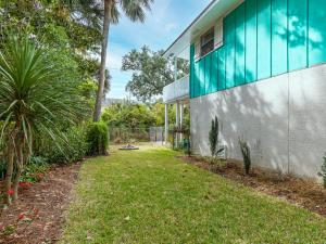 a house with a grass yard next to a building at Castaway Cottage in Tybee Island