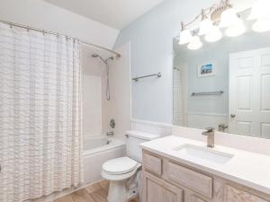 a white bathroom with a toilet and a sink at Catch A Wave in Tybee Island +40 photos