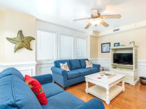 a living room with a blue couch and a tv at Captains Watch 11 in Tybee Island