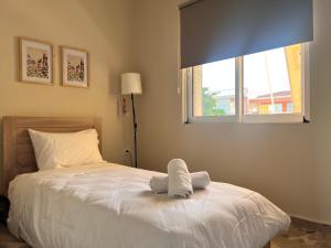 Un dormitorio con una cama blanca con una ventana. en Kyklamino Apartment, en Loutra Oraias Elenis