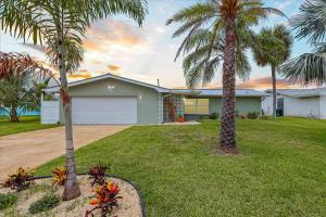 a house with two palm trees in a yard at 106 La Riviere Rd in Cocoa Beach