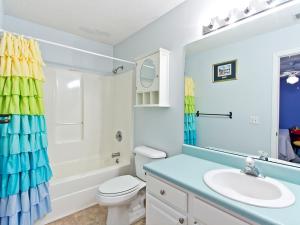 a bathroom with a sink and a toilet and a mirror at Beach Song in Tybee Island +39 photos