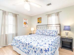 a bedroom with a blue and white bed and windows at Beach Song in Tybee Island