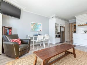 a living room with a leather chair and a table at Beach Racquet B202 in Tybee Island