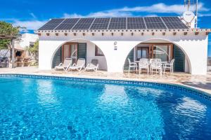 a house with a solar roof and a swimming pool at Villa Chiquita in Cala'n Porter +6 photos