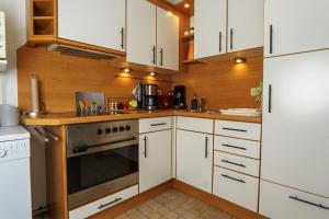Una cocina con gabinetes blancos y una estufa. en Gleich hinterm Deich 2, en Friedrichskoog 16 fotos más