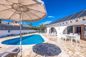a villa with a swimming pool and an umbrella at Villa Chiquita in Cala'n Porter