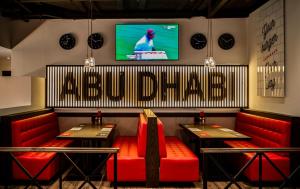 a restaurant with red chairs and a television on the wall at Holiday Inn Abu Dhabi by IHG in Abu Dhabi