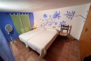 ein Schlafzimmer mit einem weißen Bett mit blauen Blumen an der Wand in der Unterkunft Montsant Wine House with Mountain Views in La Morera de Montsant + 71 Fotos