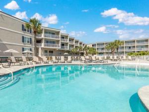 a swimming pool with chairs and a building at Beach House 413 in Tybee Island