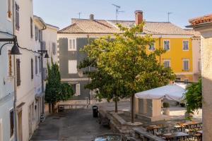 Una calle con mesas y un árbol y edificios. en Casa Angelina, en Vrsar