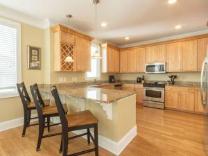una cocina con armarios de madera, mesa y sillas en All About Tybee, en Tybee Island