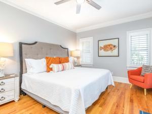 Un dormitorio con una cama blanca y una silla roja. en A Wave From It All, en Tybee Island