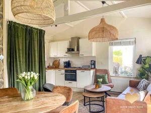 a living room with a table and a kitchen at The Soultree - Stylish nature cottage near Schoorl dunes & Bergen beach in Warmenhuizen
