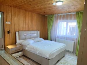 a bedroom with a white bed and a window at Çay Pansiyon in Uzungöl