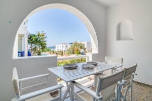 una mesa y sillas en un balcón con un arco en Olive & Stone Residence, en Aliki