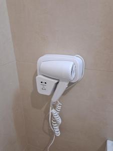 un sèche-cheveux blanc accroché au mur dans l'établissement La casa di Titty, à Reggio de Calabre