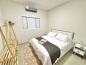 a bedroom with a bed with white sheets and a window at Casa Lago da Dinda 3 in Espirito Santo Do Pinhal