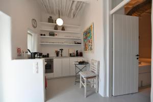 a white kitchen with a table and a white refrigerator at Kariki Green Triantaros Tinos in Triandáros