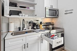 a white kitchen with a sink and a microwave at Apt Near Downtown Desk Wifi Tvs Games Pets in Houston +10 photos