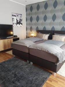 a bedroom with two beds and a flat screen tv at Einführungspreis Gemütliche Auszeit - Designwohnung - 4 Sterne Hotelboxspringbetten - Küche - Familie - Erdgeschoss in Recklinghausen