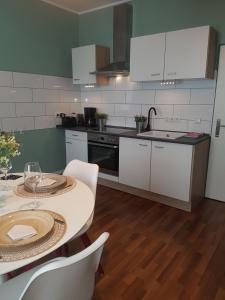 a kitchen with white cabinets and a table with chairs at Einführungspreis Gemütliche Auszeit - Designwohnung - 4 Sterne Hotelboxspringbetten - Küche - Familie - Erdgeschoss in Recklinghausen