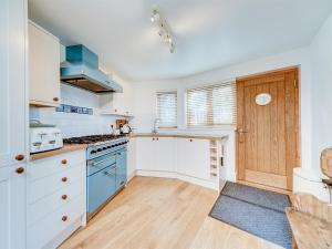 Una cocina con gabinetes blancos y electrodomésticos azules. en 2 Bed in Cowes IC018, en Cowes