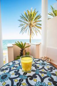 a glass bowl of yellow liquid sitting on a table on the beach at Alma's Dream Estepona in Estepona