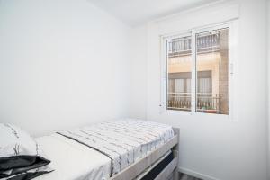 a white bedroom with a bed and a window at Ecos del Mar - Darya in Peniscola