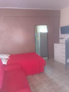 a bedroom with a red bed and a refrigerator at Kitnet PRAIA GRANDE in Arraial do Cabo