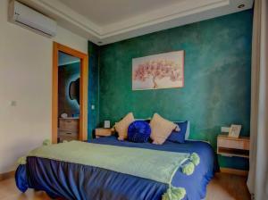 a bedroom with a blue bed with a green wall at Cosy Beach home swimming pool in Tamraght Ouzdar +16 photos