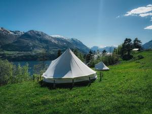 two tents in a field with a lake and mountains at Glamping Kalhagen in Vangsbygd