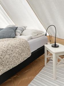 a bedroom with a bed and a table with a lamp at Glamping Kalhagen in Vangsbygd +17 photos