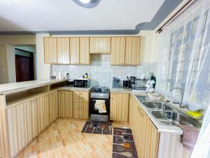 a kitchen with wooden cabinets and a sink and a stove at The Kulta Spot Executive Living in Thika +7 photos