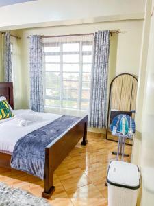 a bedroom with a bed and a chair and a window at The Kulta Spot Executive Living in Thika