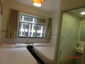 2 camas en una habitación con ventana y espejo en Li Cheng Guesthouse en Hong Kong