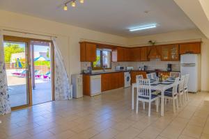 a kitchen with a table and chairs and an open door at Villa Heracles by Villa Plus in Peyia