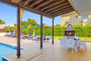 a patio with tables and chairs and a swimming pool at Villa Heracles by Villa Plus in Peyia