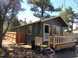 een grijs klein huisje met een veranda en een hek bij Lazy Pines in Sugarloaf