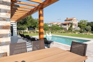 un patio con tavolo e sedie accanto alla piscina di Villa Veduta a Bale (Valle)