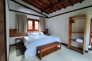 a bedroom with a large white bed and a window at Vida Cajuína Maraú in Marau