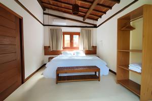a bedroom with a large white bed and a table at Vida Cajuína Maraú in Marau