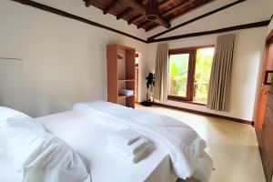 a white bed in a room with a window at Vida Cajuína Maraú in Marau