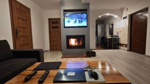 a living room with a fireplace and a tv on the wall at Ranczo Bieszczady 2 - Domek z Sauną i Jacuzzi in Mrzygłód