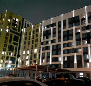 a large building at night with cars parked in front at Respublika LUX Уютная 2-комнатная квартира in Astana