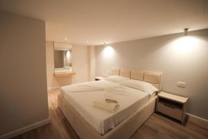 une chambre avec un grand lit blanc avec un miroir dans l'établissement Duplex City, à Durrës