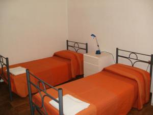 2 Betten mit orangefarbener Bettwäsche in einem Zimmer in der Unterkunft Villa Marina Scoglitti in Scoglitti
