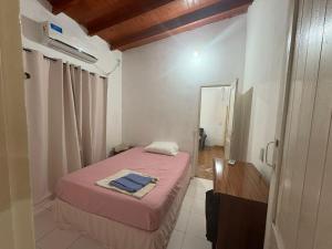 a small bedroom with a pink bed and a mirror at Las Azaleas in Puerto Iguazú
